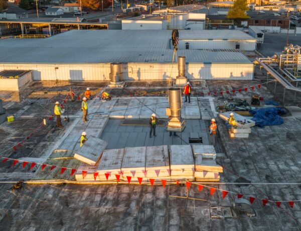 aerial photo of workers replacing panels on the roof of a plant